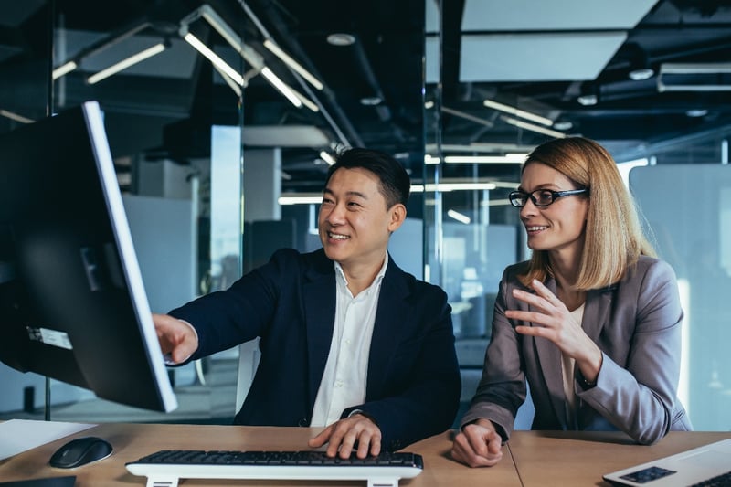 Two business people review trucking data and analytics together in an office. 