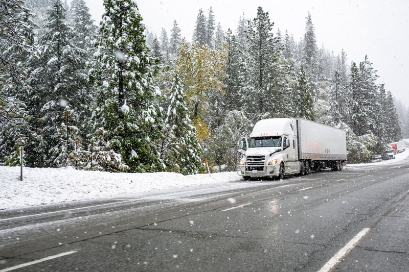 A semi-truck drives down a snowy highway in Colorado. 