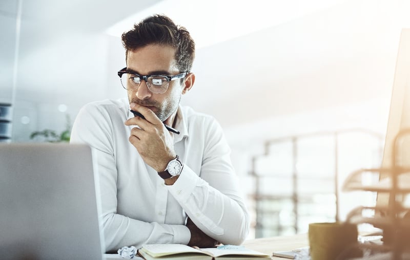 A business man types on a keyboard while sitting in an office. 