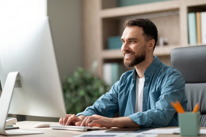 A business man reviews analytics on a desktop computer in an office. 