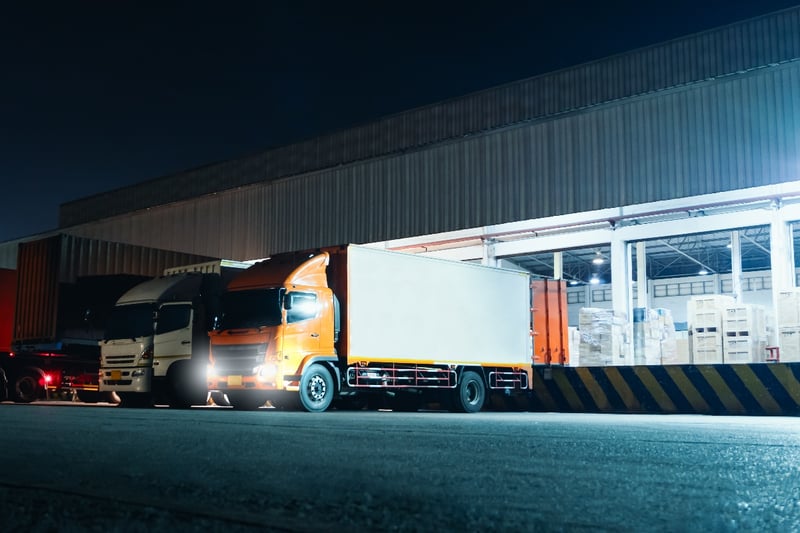 A group of semi-trucks being unloaded at a distribution center.