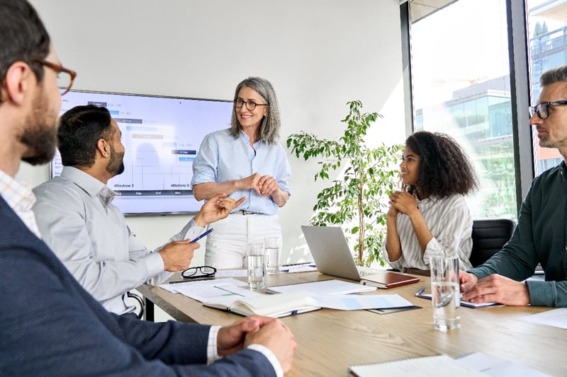 A female team member reviews data with colleagues in an office. 